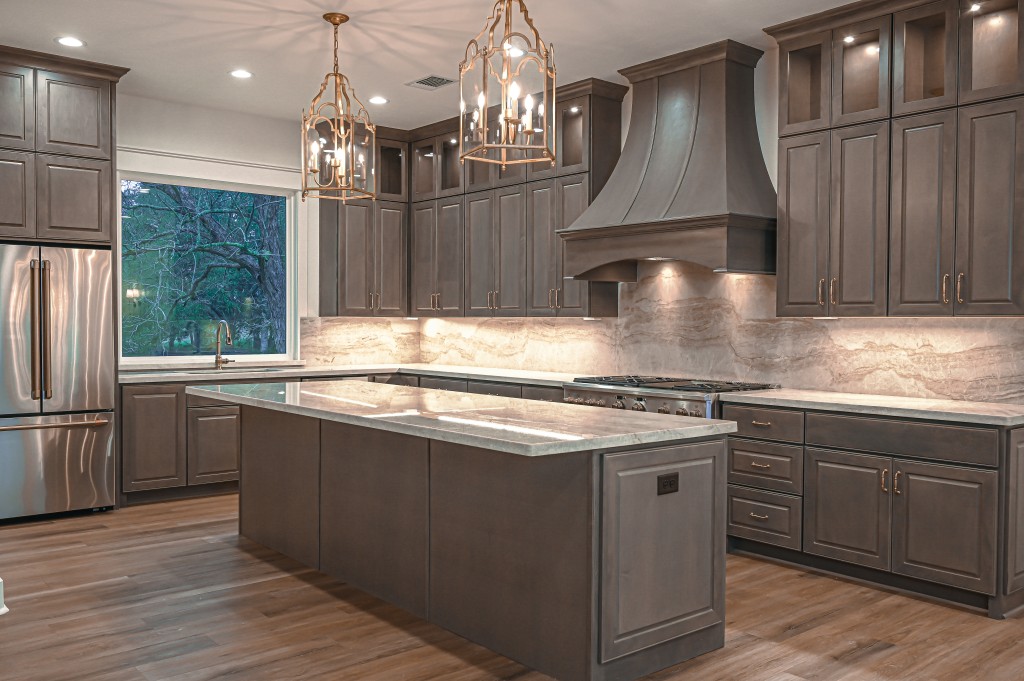 Beautiful custom built kitchen with brown cabinets and gold accent lighting.
