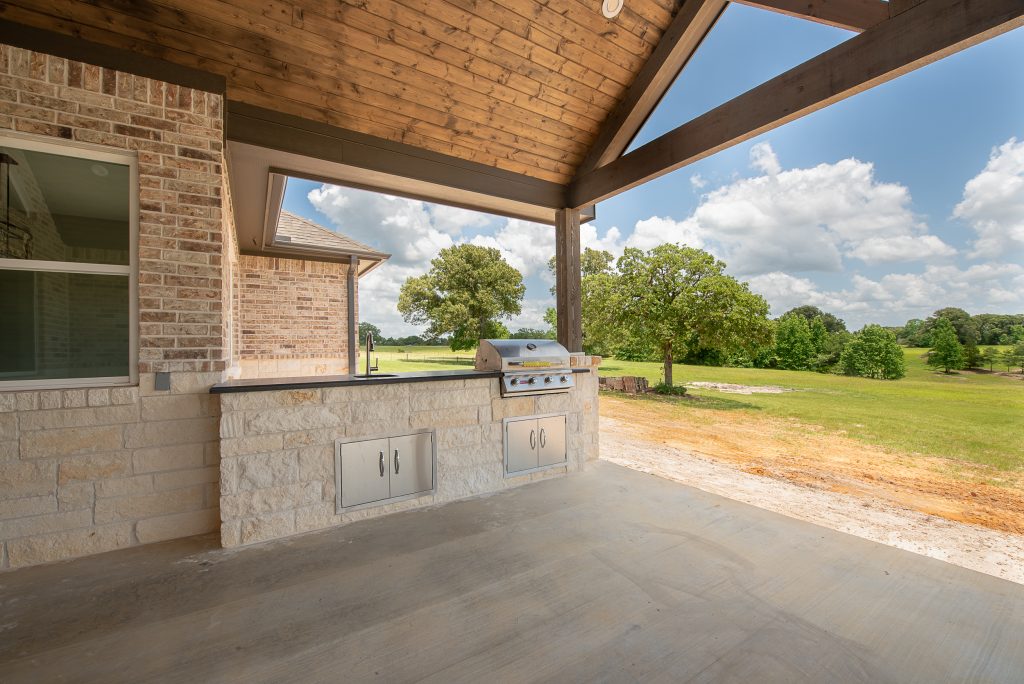 Custom built-in grill with fridge in outdoor living space.