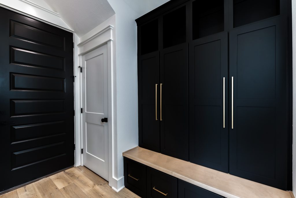Black custom built cabinets in a mud room that contrast with white walls.